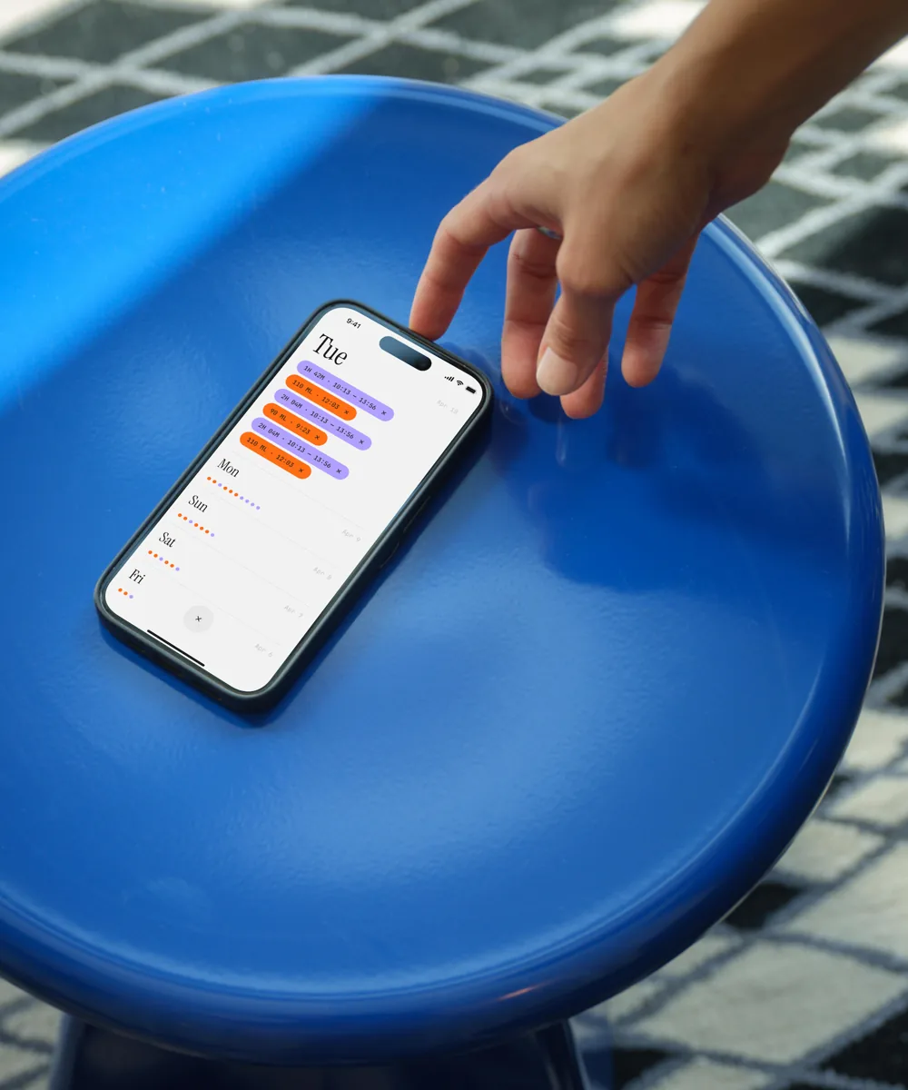 Logging a feed on Tiny Bean, phone resting on a poolside table